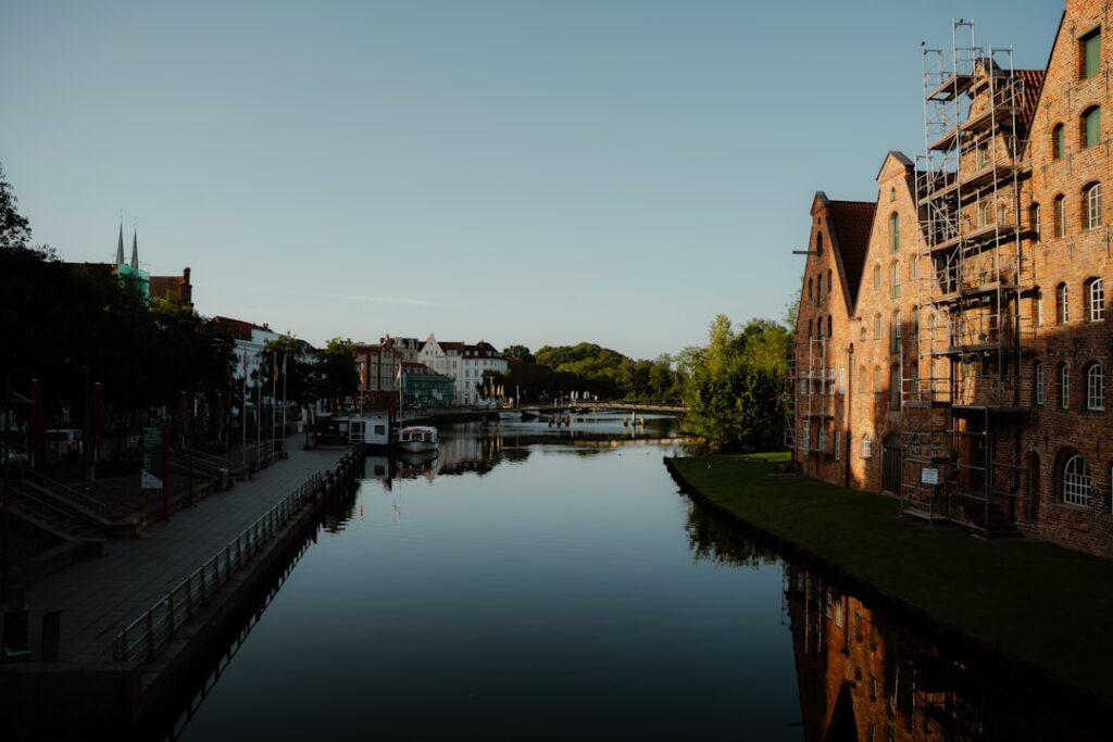 Buildings line a calm river with reflections.