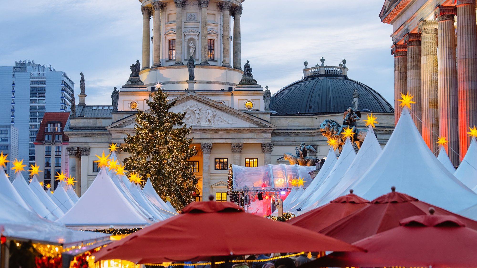 Christmas market stalls with lit stars and a tree in front of the German Cathedral on Gendarmenmarkt, Berlin
