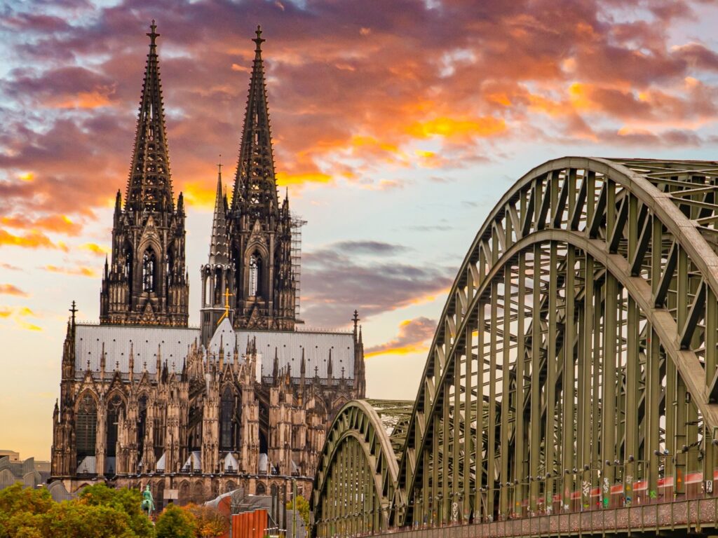 Twin Gothic spires of Cologne Cathedral against a sunset sky