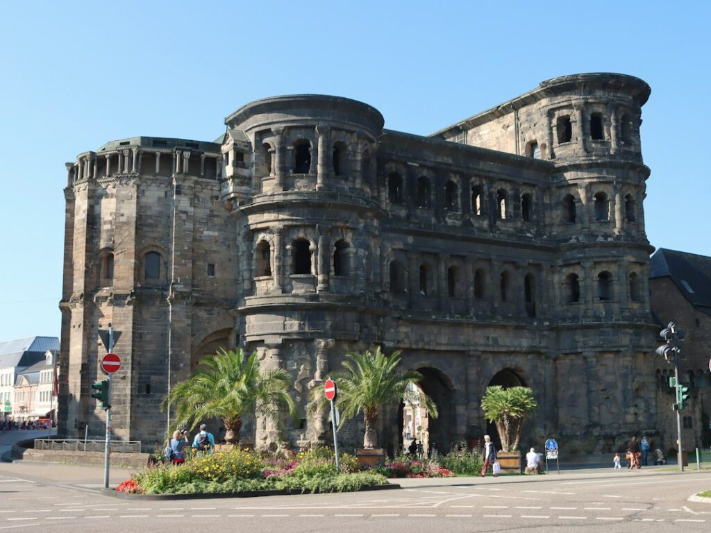 Ancient roman gate with palm trees and people